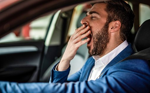 image-tired-mid-adult-businessman-driving-a-car-and-yawning