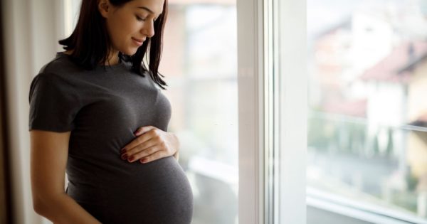 image-portrait-of-young-happy-pregnant-woman-standing-by-the-window
